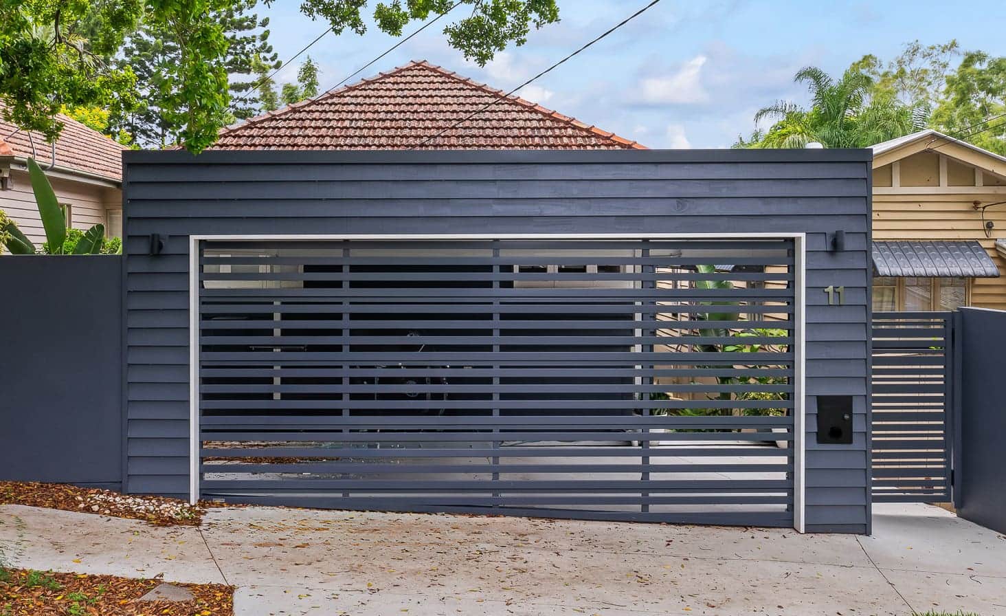 Dark aluminium slat gate and matching fence on a Brisbane driveway