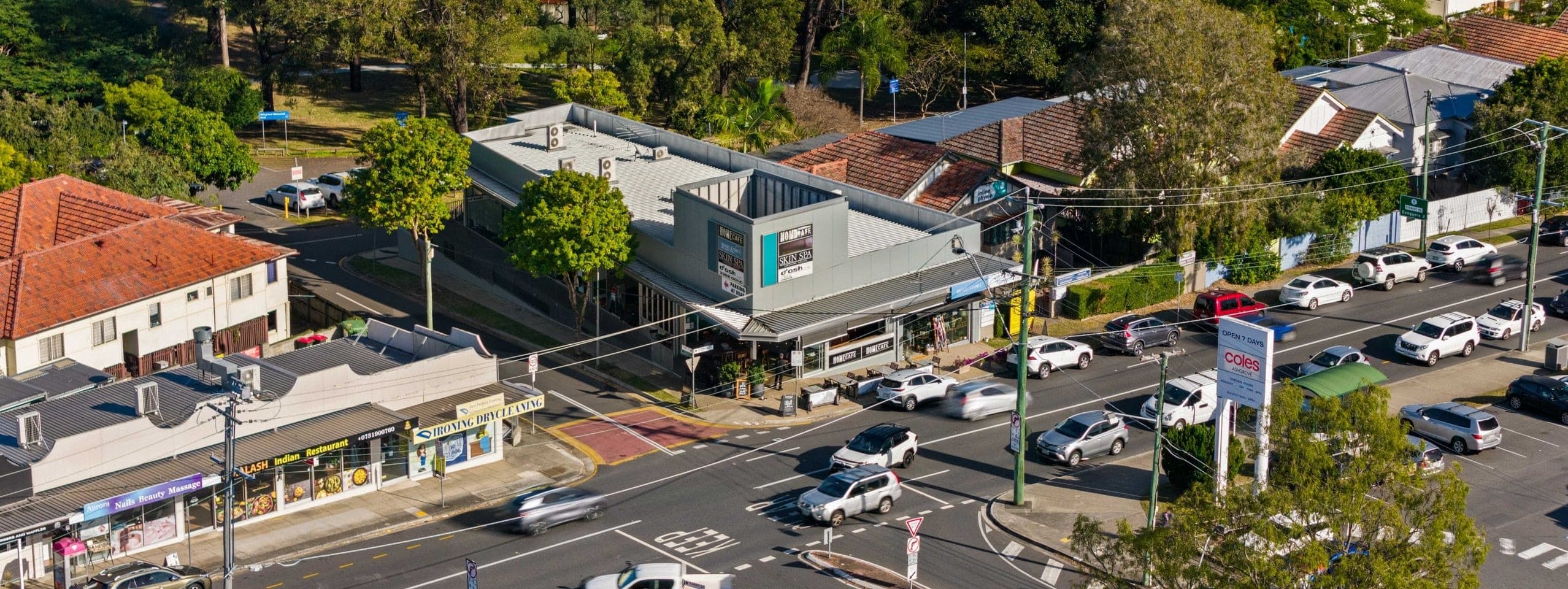 A leafy Ashgrove street with a classic Queenslander home and timber garage door